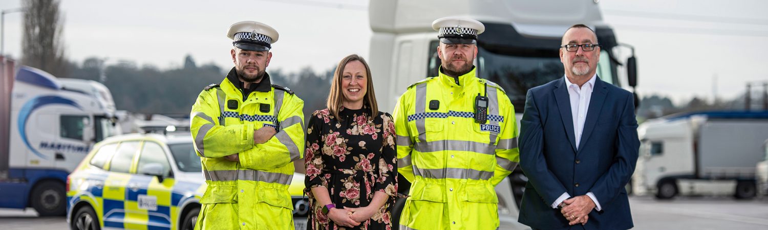Two police officers, a women and male stood in front of HGV