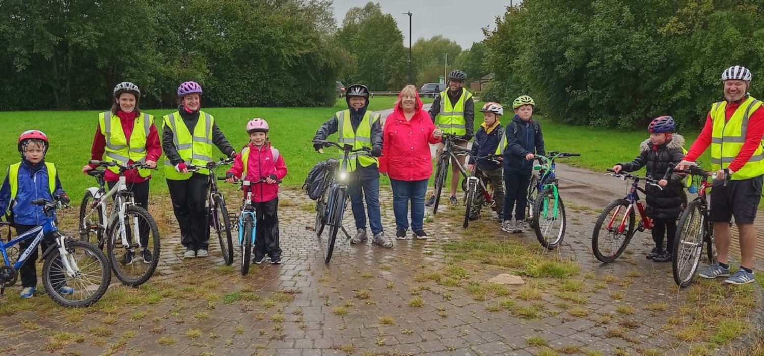 A number of adults and children standing with their bikes